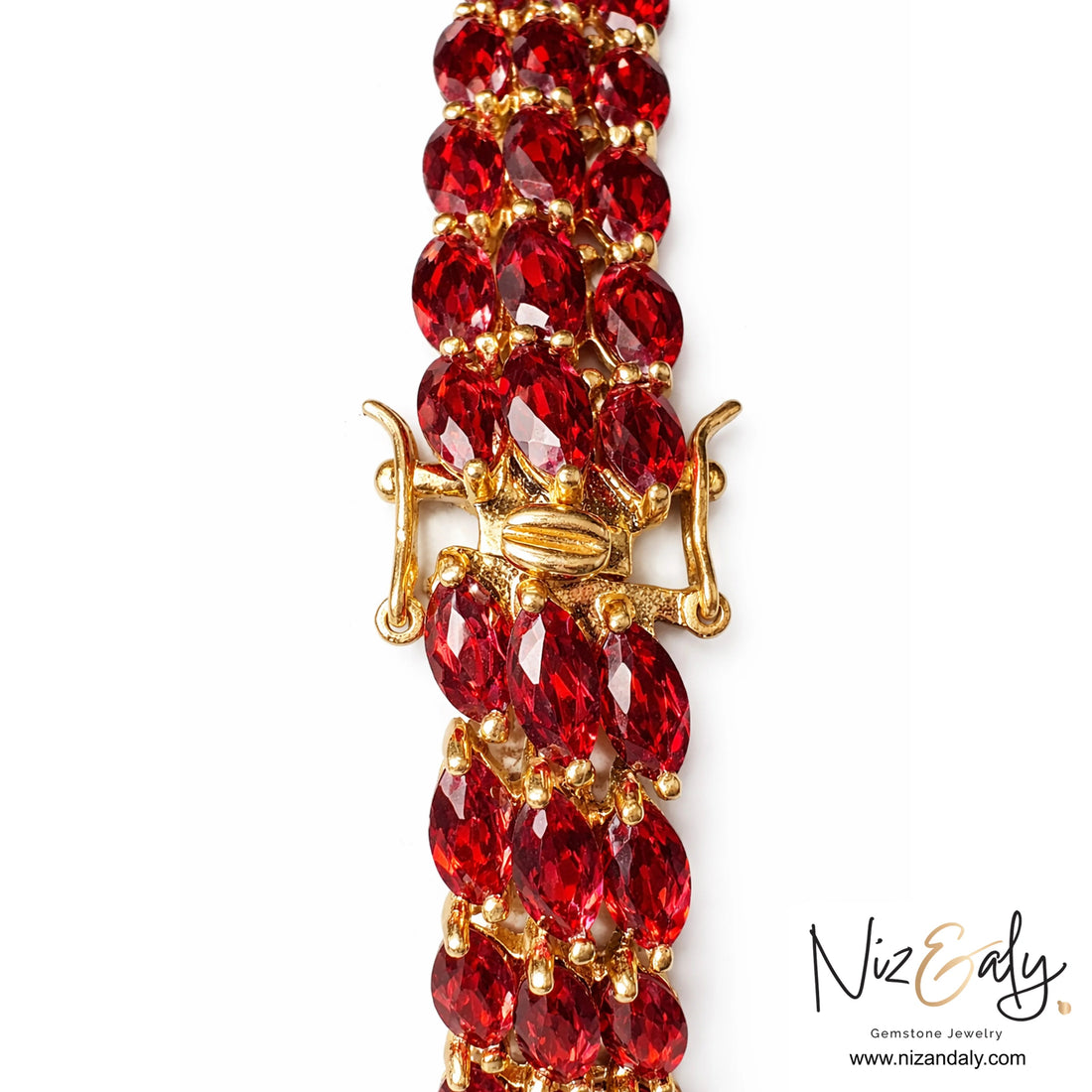 Bracelet with red gemstones and gold clasp on a white background, branded 'Niz & Aly'.