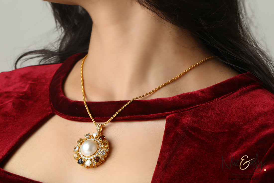 Niz & Aly gold-tone pendant necklace featuring a central pearl surrounded by multi-colored gemstones on a rope chain.