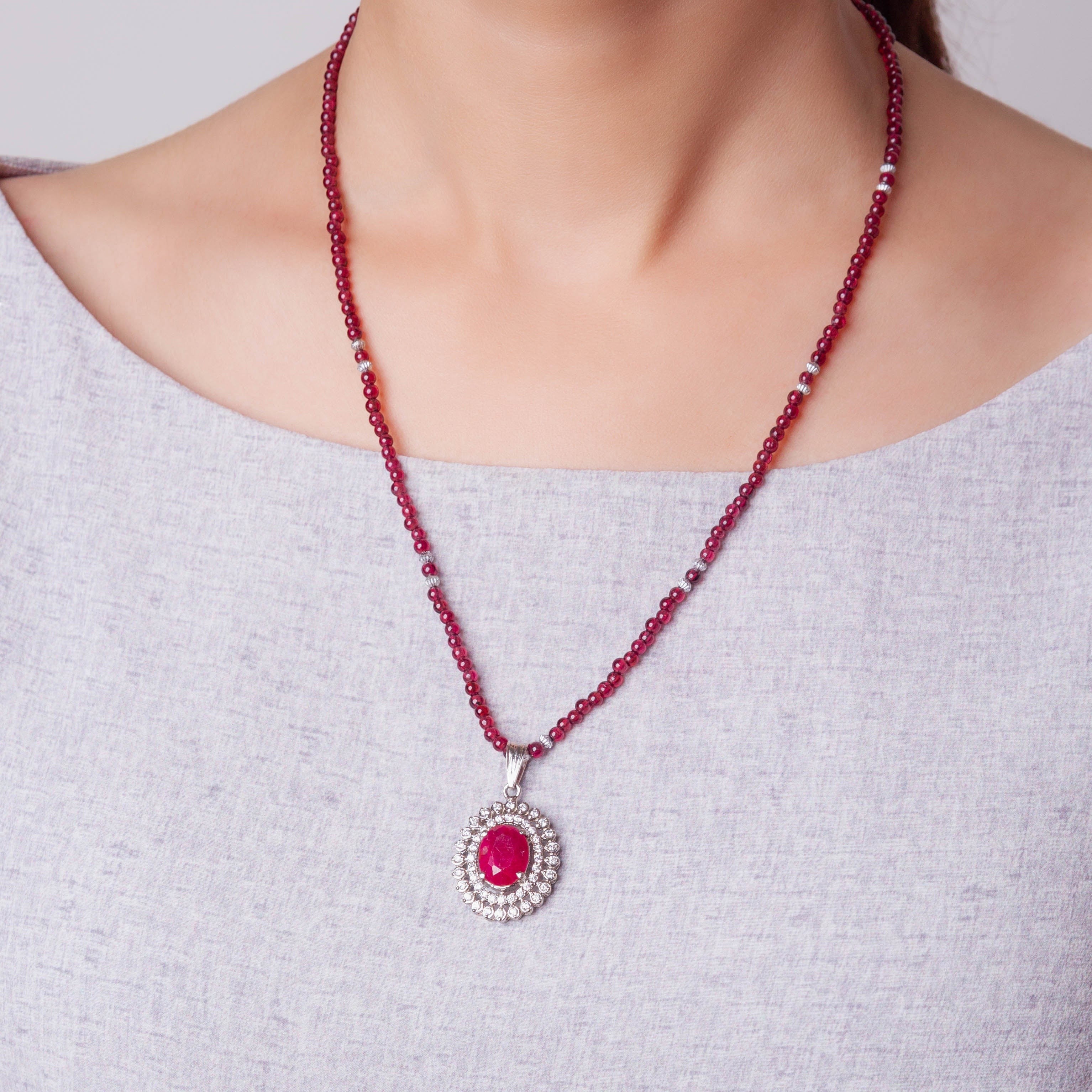Niz & Aly African ruby pendant featuring a vibrant red oval stone surrounded by diamonds on a delicate garnet bead chain