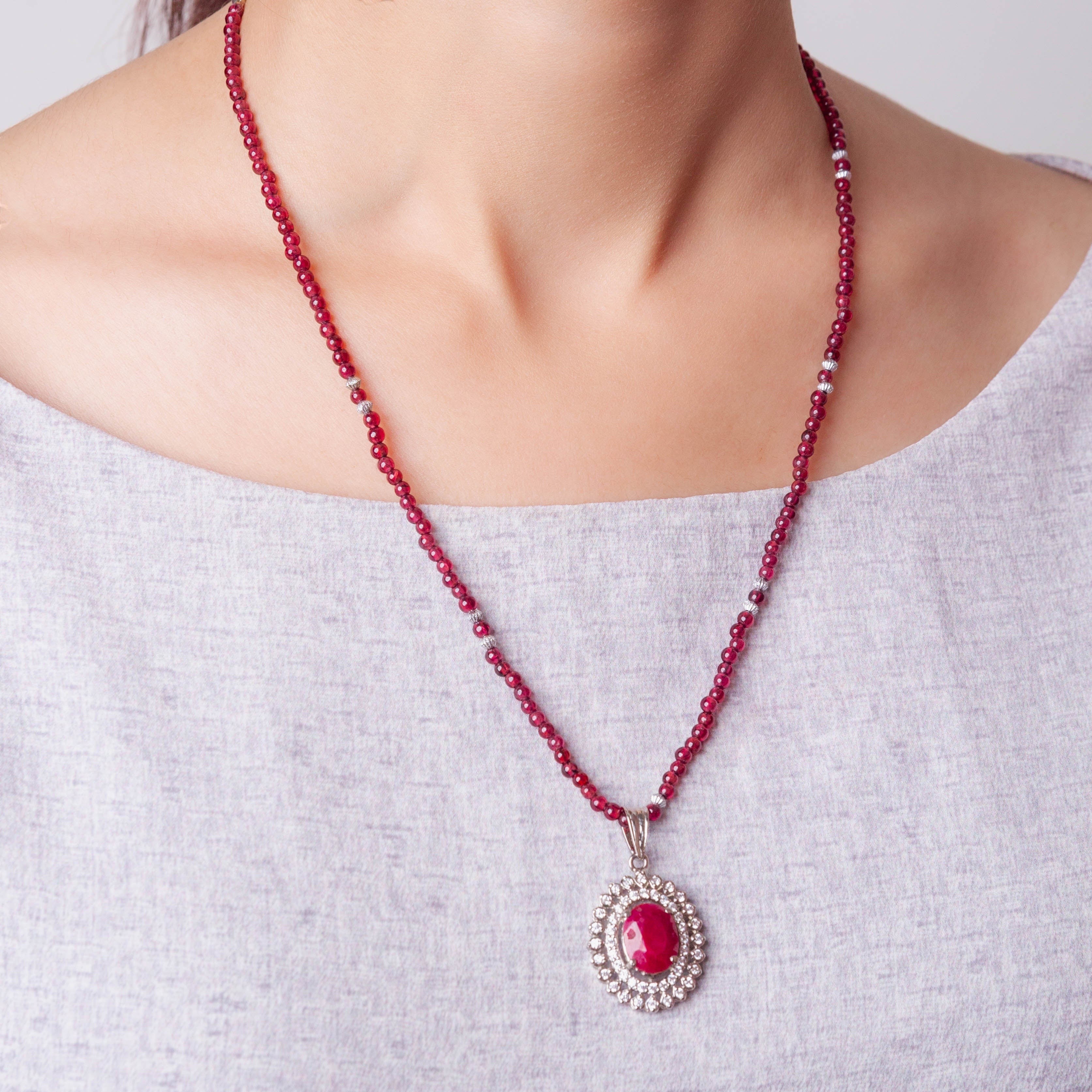 Niz & Aly African ruby pendant featuring a halo of diamonds on a delicate garnet bead necklace worn around the neck.
