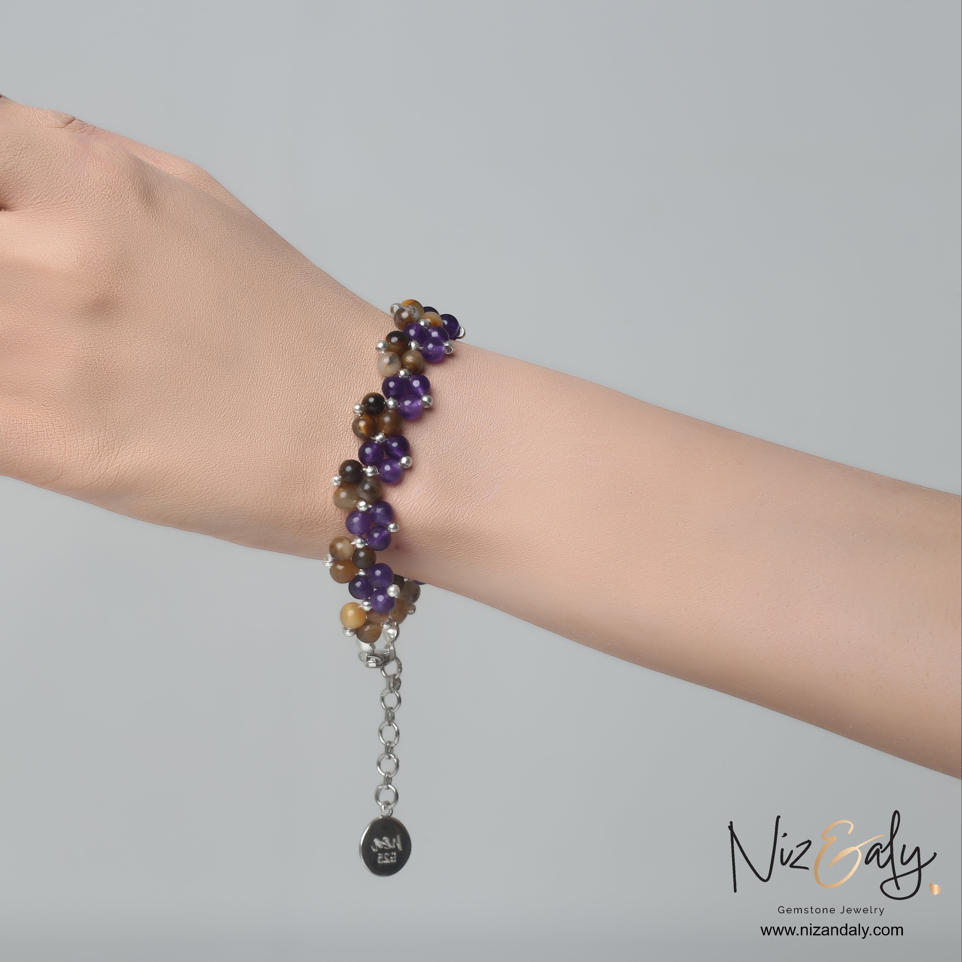 Niz & Aly amethyst and brown banded agate beaded bracelet worn on a wrist with silver chain and charm detail.