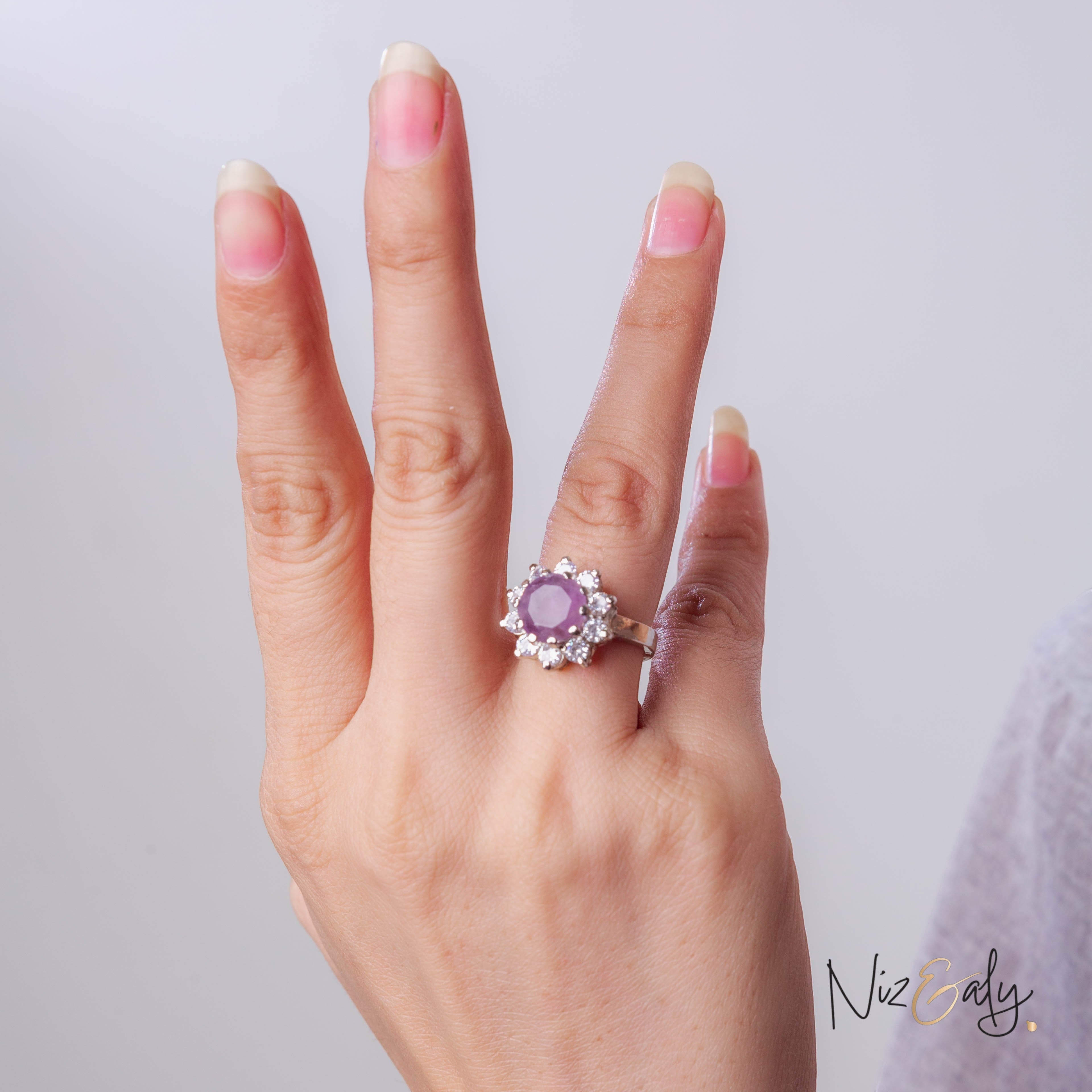 Niz & Aly amethyst ring with a round violet stone surrounded by small clear crystals on a woman's finger