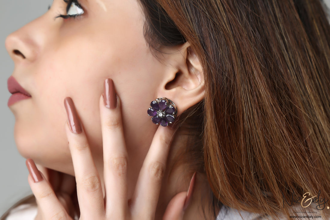 Niz & Aly amethyst flower ear stud worn by a woman, featuring purple gemstone petals and a central clear stone.