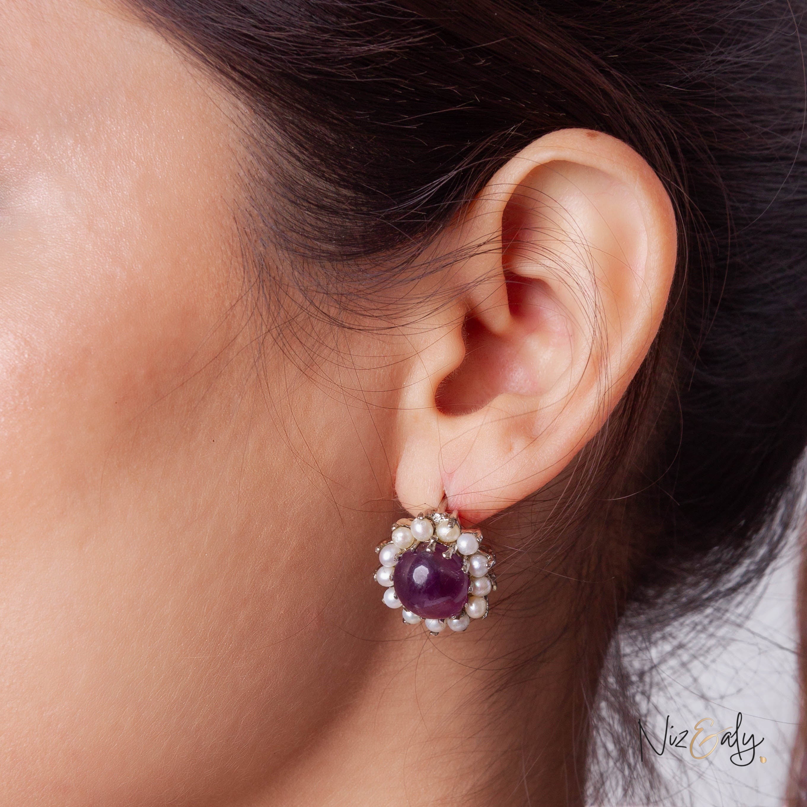 Niz & Aly amethyst gemstone earring surrounded by a halo of small white freshwater pearls worn on a woman's ear
