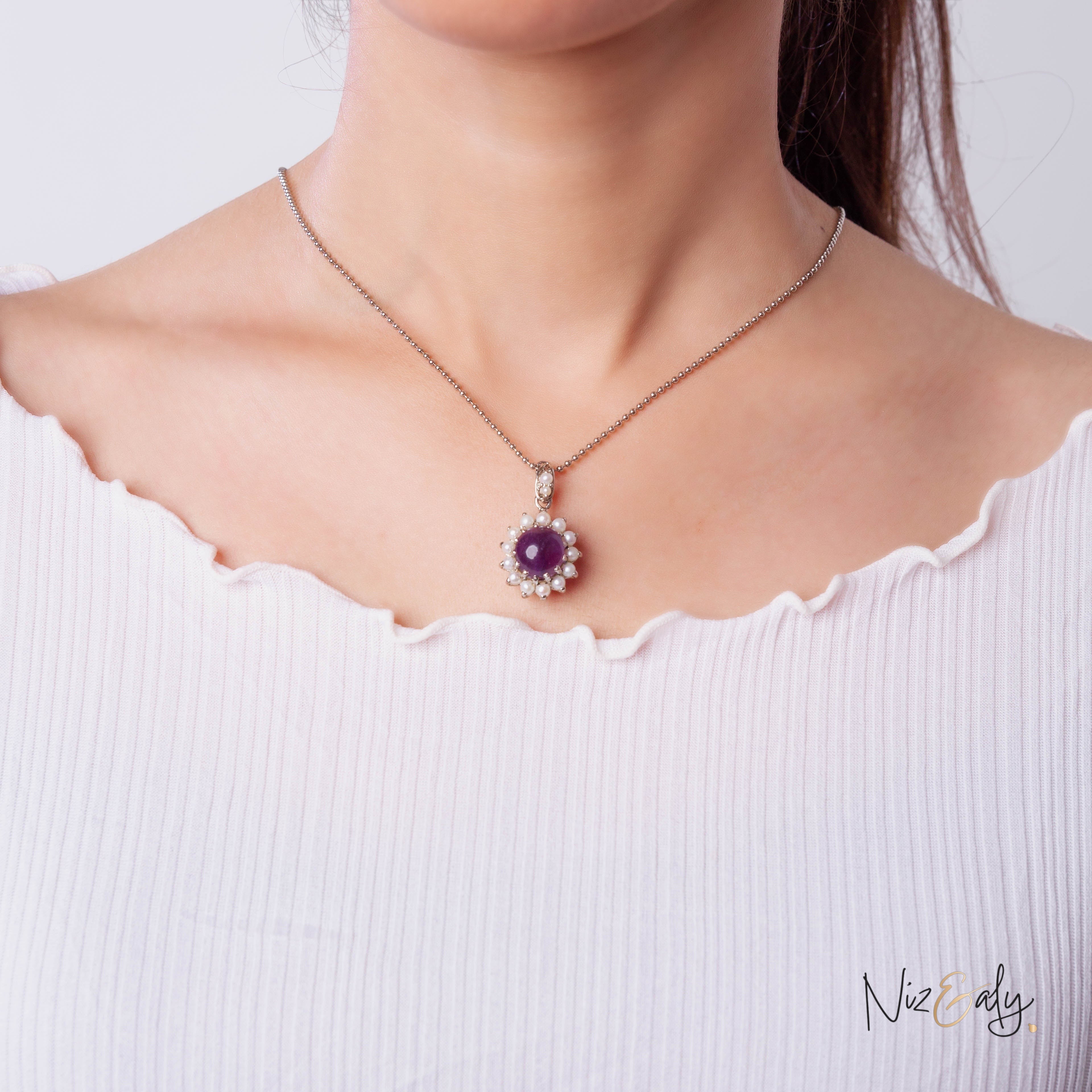 Niz & Aly necklace featuring a round purple amethyst stone surrounded by a halo of small white freshwater pearls.