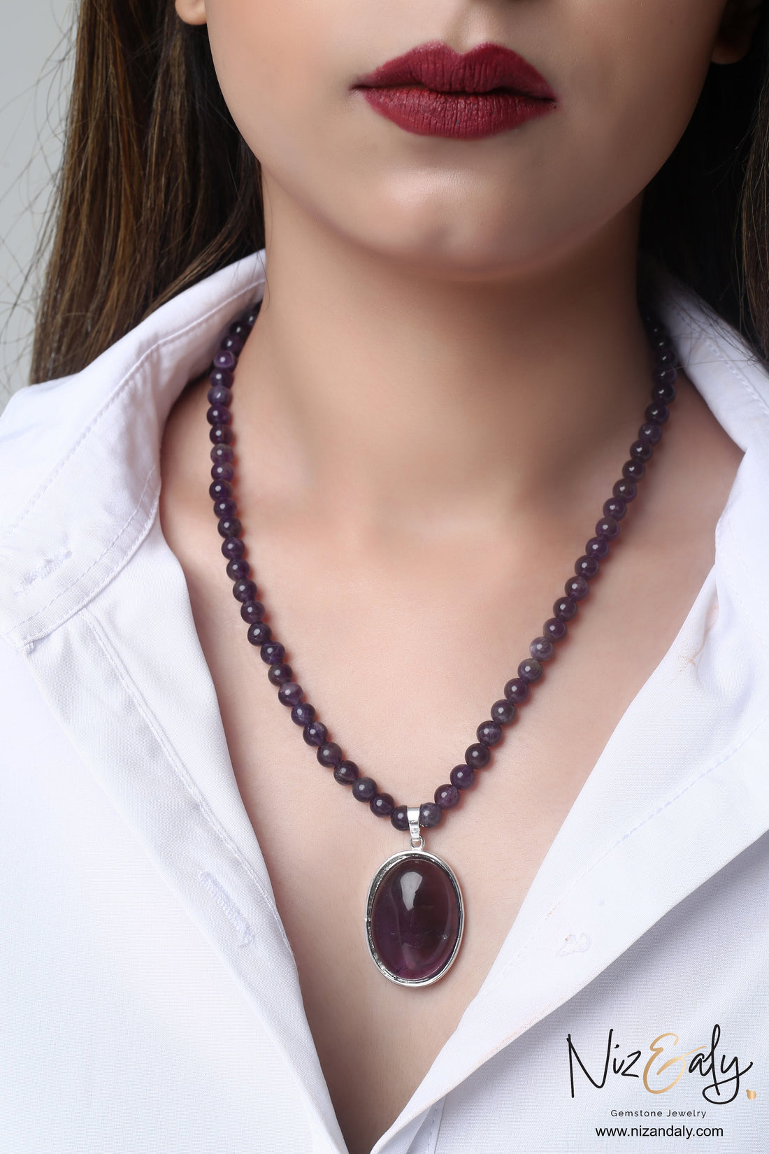 Niz & Aly amethyst gemstone necklace featuring a large polished violet pendant on a strand of natural purple beads