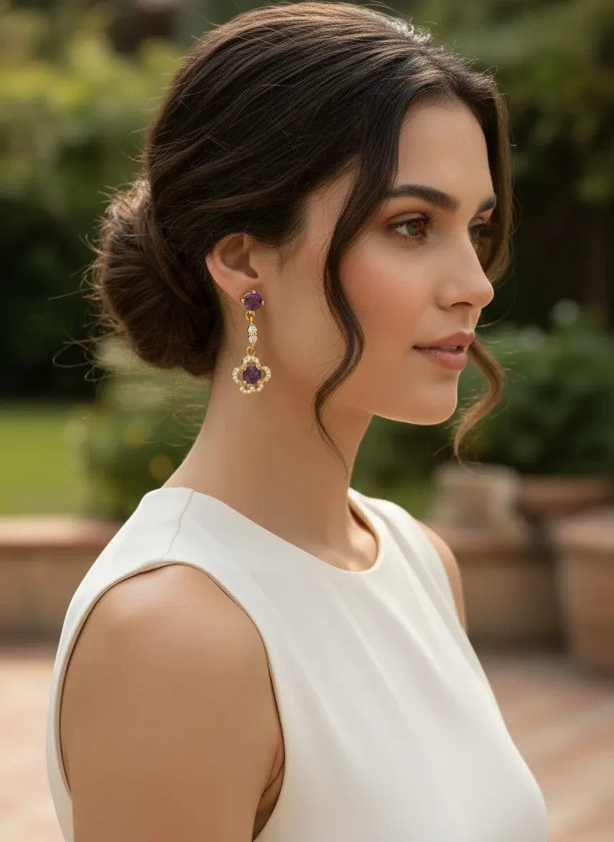 Niz & Aly delicate gold-plated ear drops featuring faceted purple amethyst gemstones worn by a woman in a white dress.