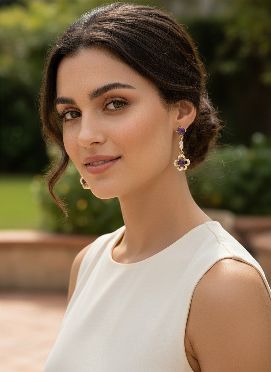 Niz & Aly delicate amethyst ear drops in gold plated setting worn by a woman in a white dress.