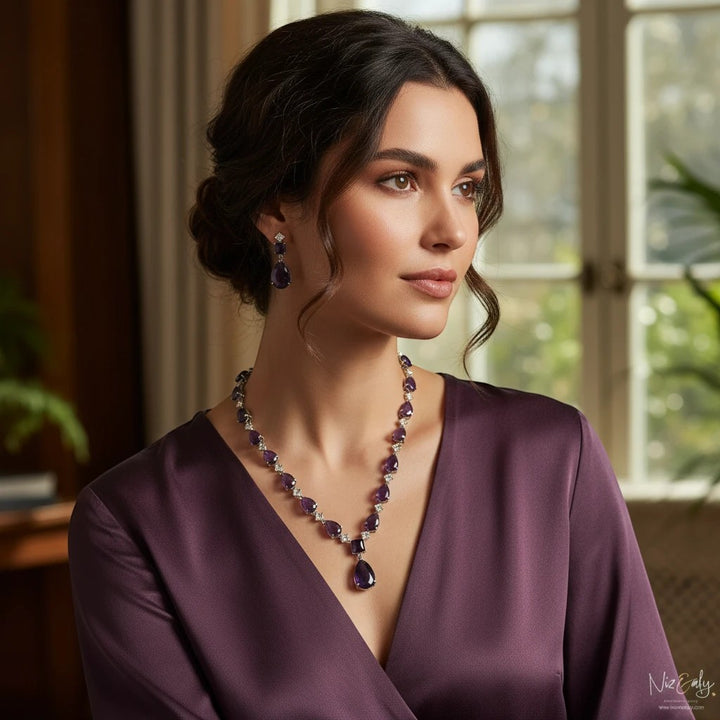 Niz & Aly droplet amethyst and Herkimer diamond necklace and earring set worn by a woman in a purple silk dress.