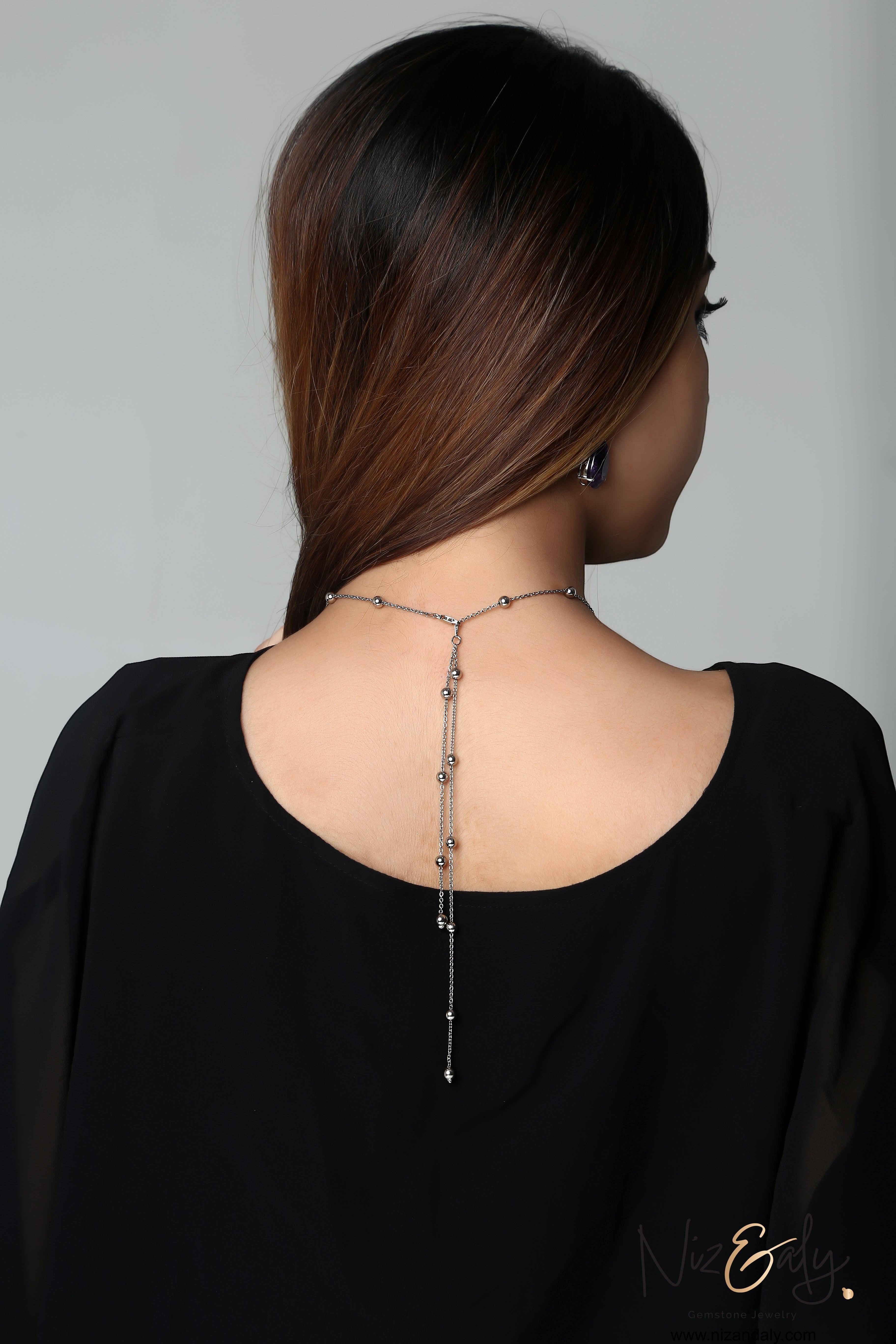 Niz & Aly amethyst and Herkimer diamond necklace set worn on a woman's back, featuring a delicate silver chain design.