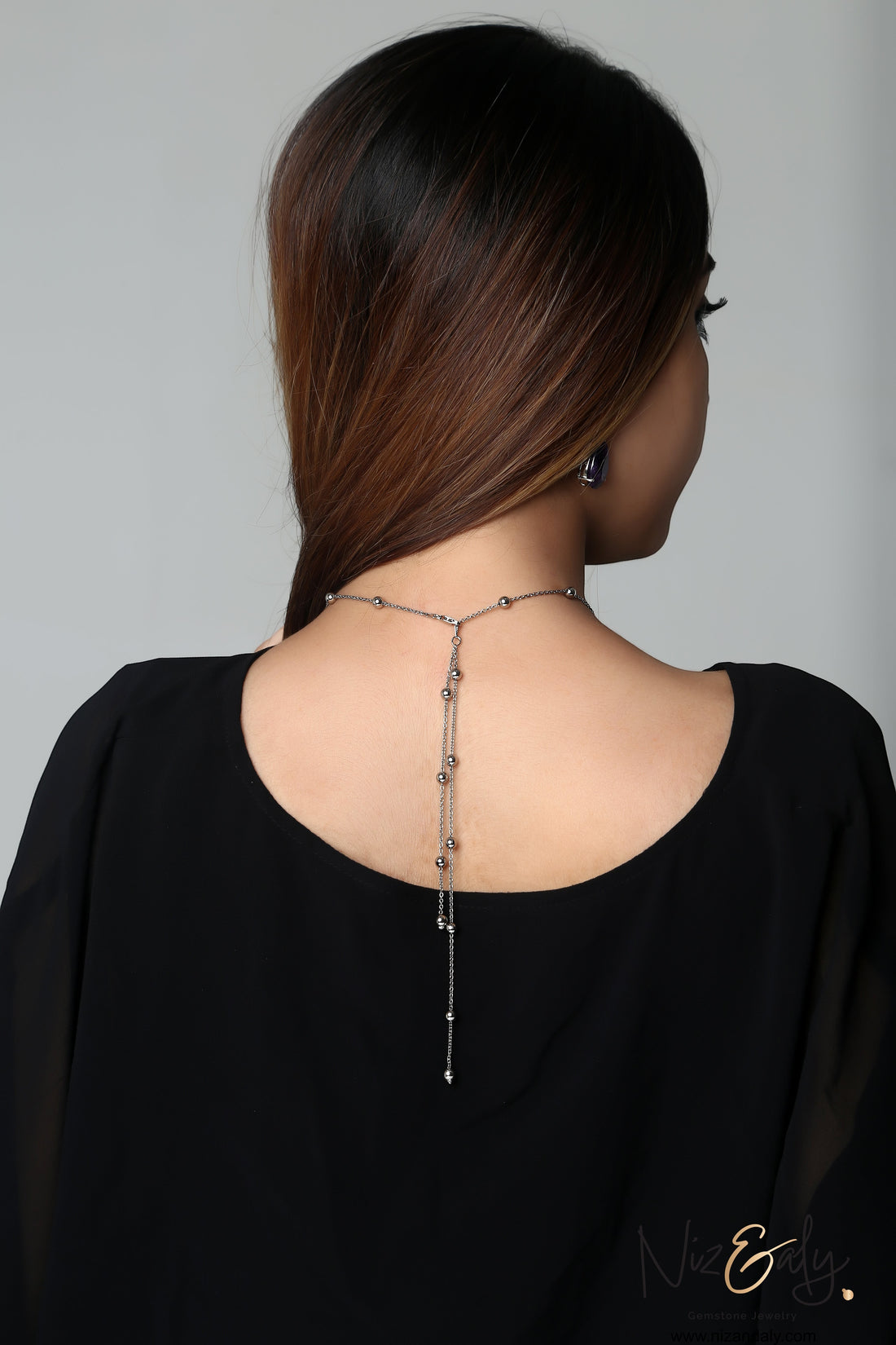 Niz & Aly amethyst and Herkimer diamond necklace set worn on a woman's back, featuring a delicate silver chain design.