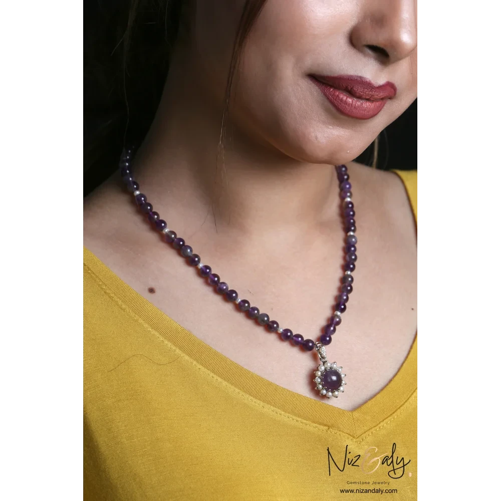 Niz & Aly amethyst and pearl pendant necklace on a beaded amethyst strand worn by a woman in a yellow top