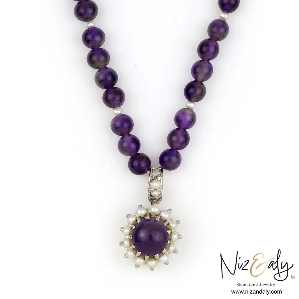 Niz & Aly amethyst and pearl pendant necklace featuring a round purple gemstone surrounded by small white pearls