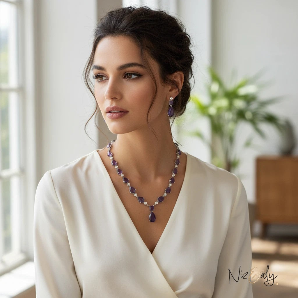 Niz & Aly necklace set featuring droplet-cut amethyst and clear quartz worn by a woman in a white blouse.