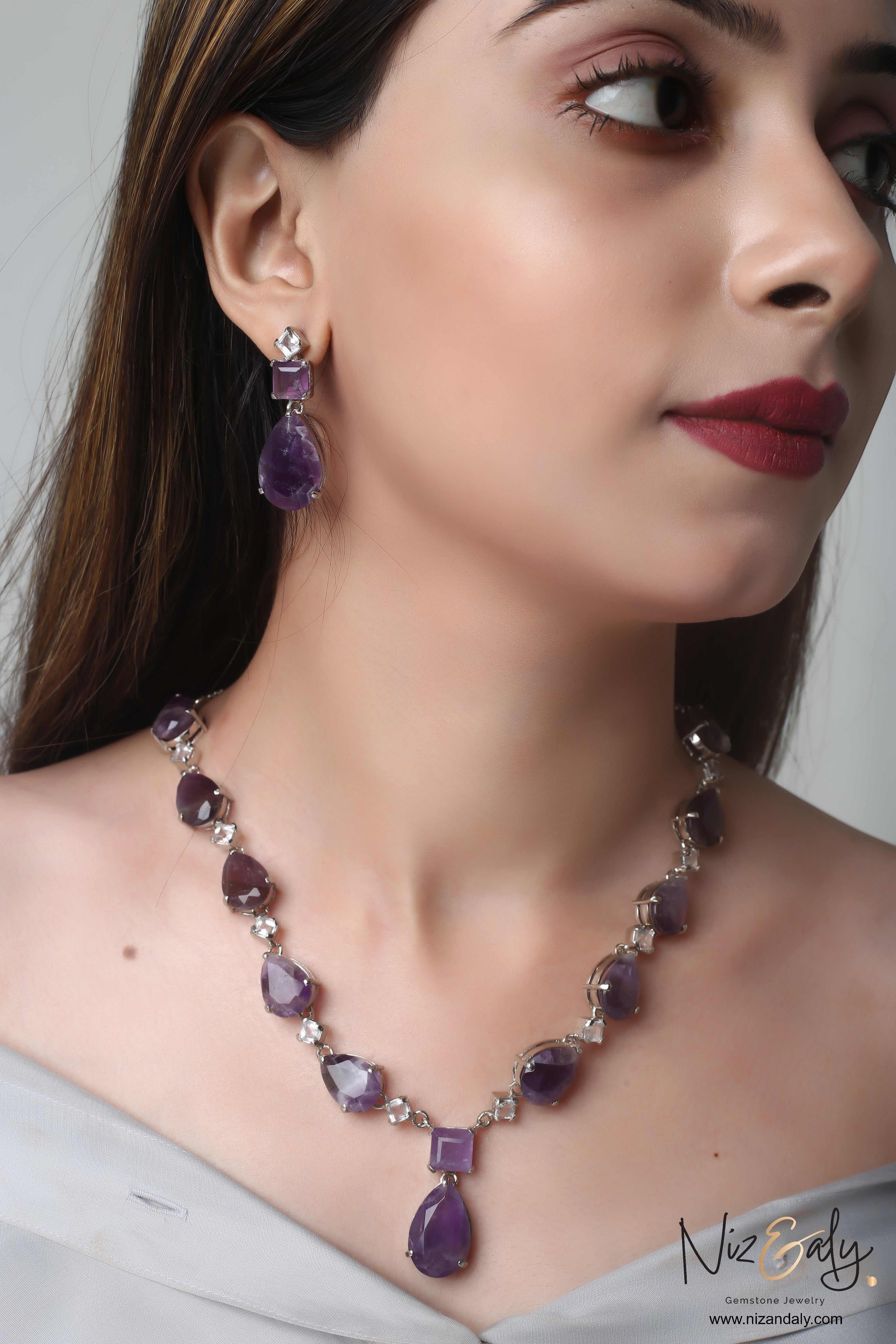Niz & Aly necklace and earring set featuring droplet-cut amethyst and clear quartz gemstones on a model.