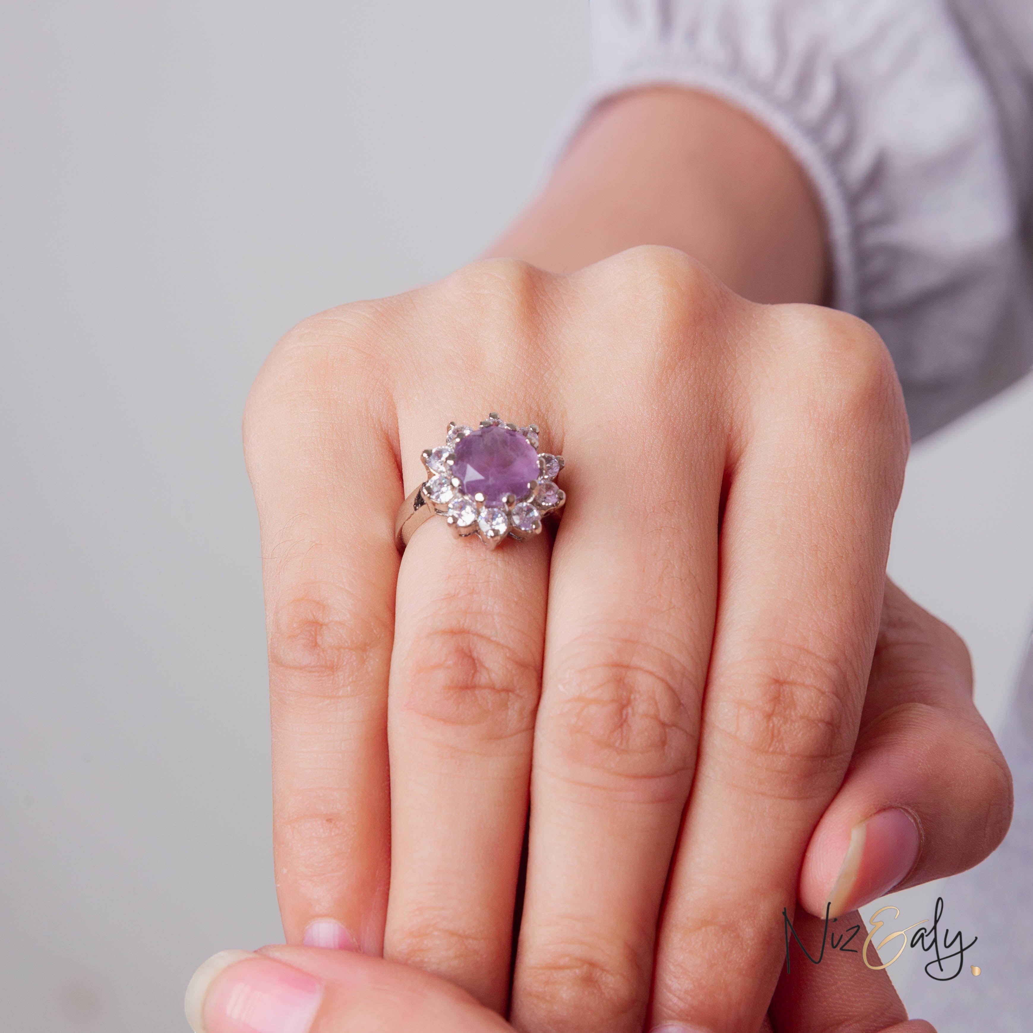 Niz & Aly amethyst ring featuring a central violet gemstone surrounded by small clear crystals on a silver band