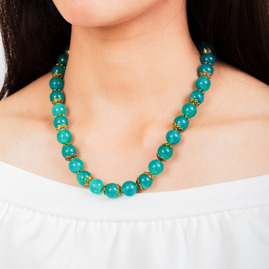 Niz & Aly aqua chalcedony beaded necklace with gold-tone spacers worn on a model in a white off-shoulder top.