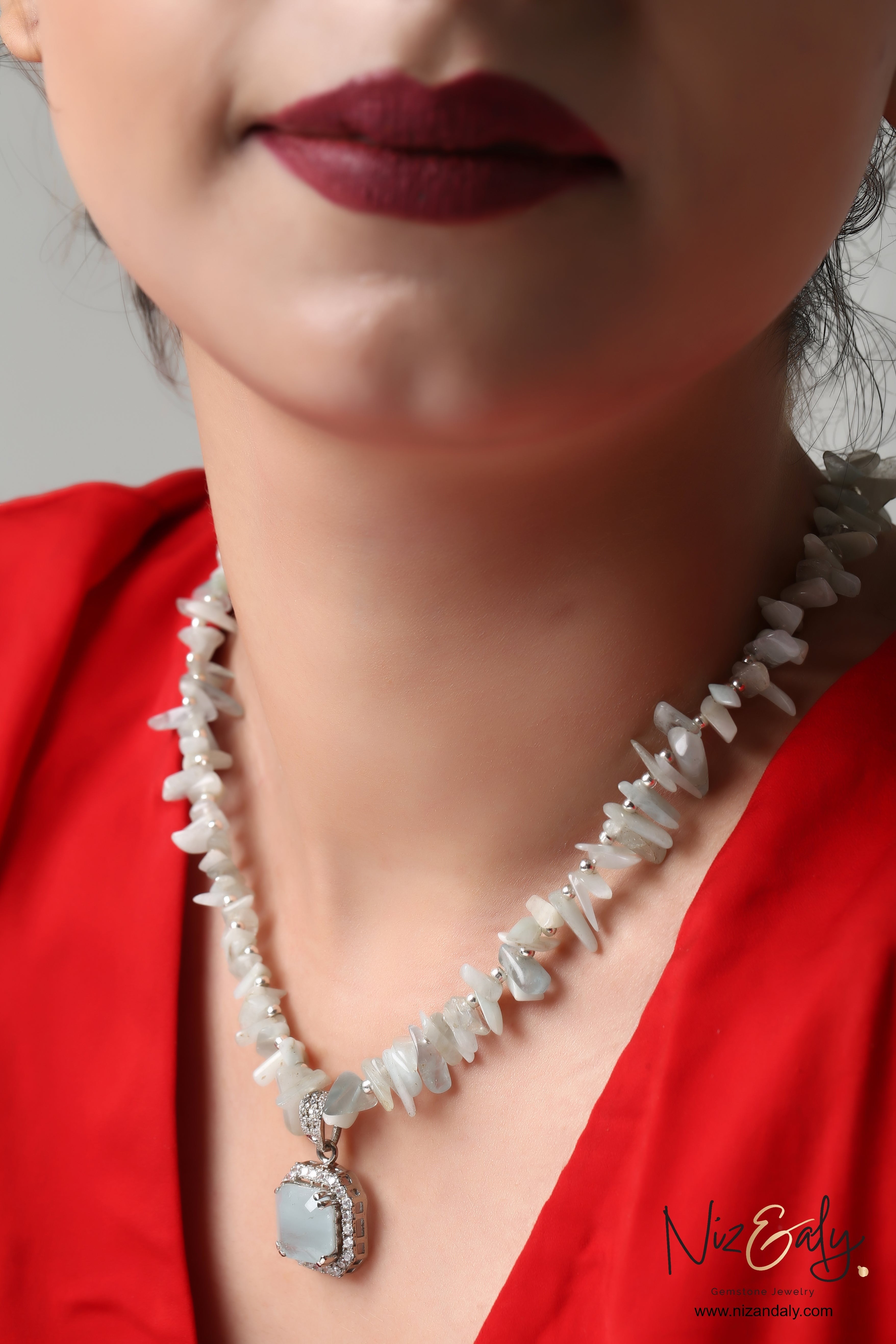 Niz & Aly natural aquamarine pendant necklace with light blue gemstone chips worn by a woman in a red top.
