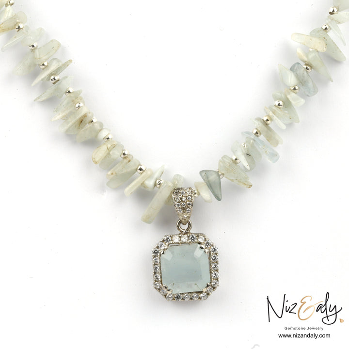 Niz & Aly aquamarine pendant necklace featuring a square gemstone pendant on a strand of raw aqua-hued chip beads.
