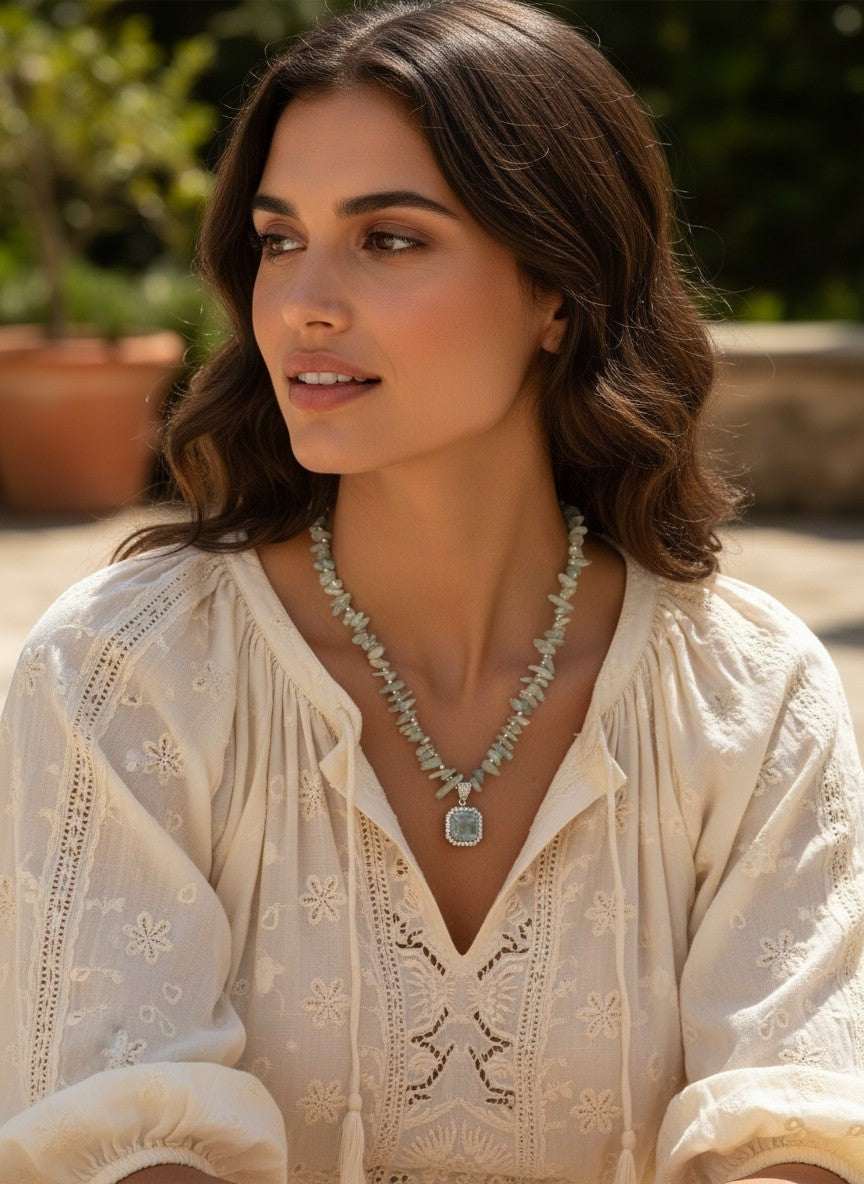 Niz & Aly natural aquamarine pendant necklace with aqua gemstone chips worn by a woman in a white embroidered blouse
