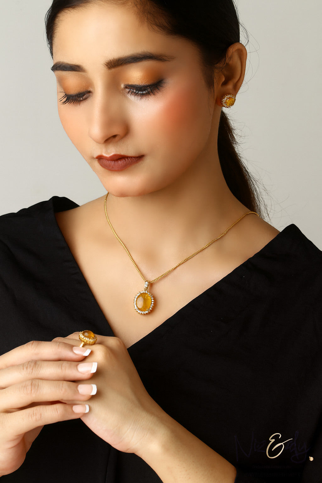 Niz & Aly genuine Baltic amber jewelry set featuring a yellow amber pendant necklace, earrings, and ring on a model.