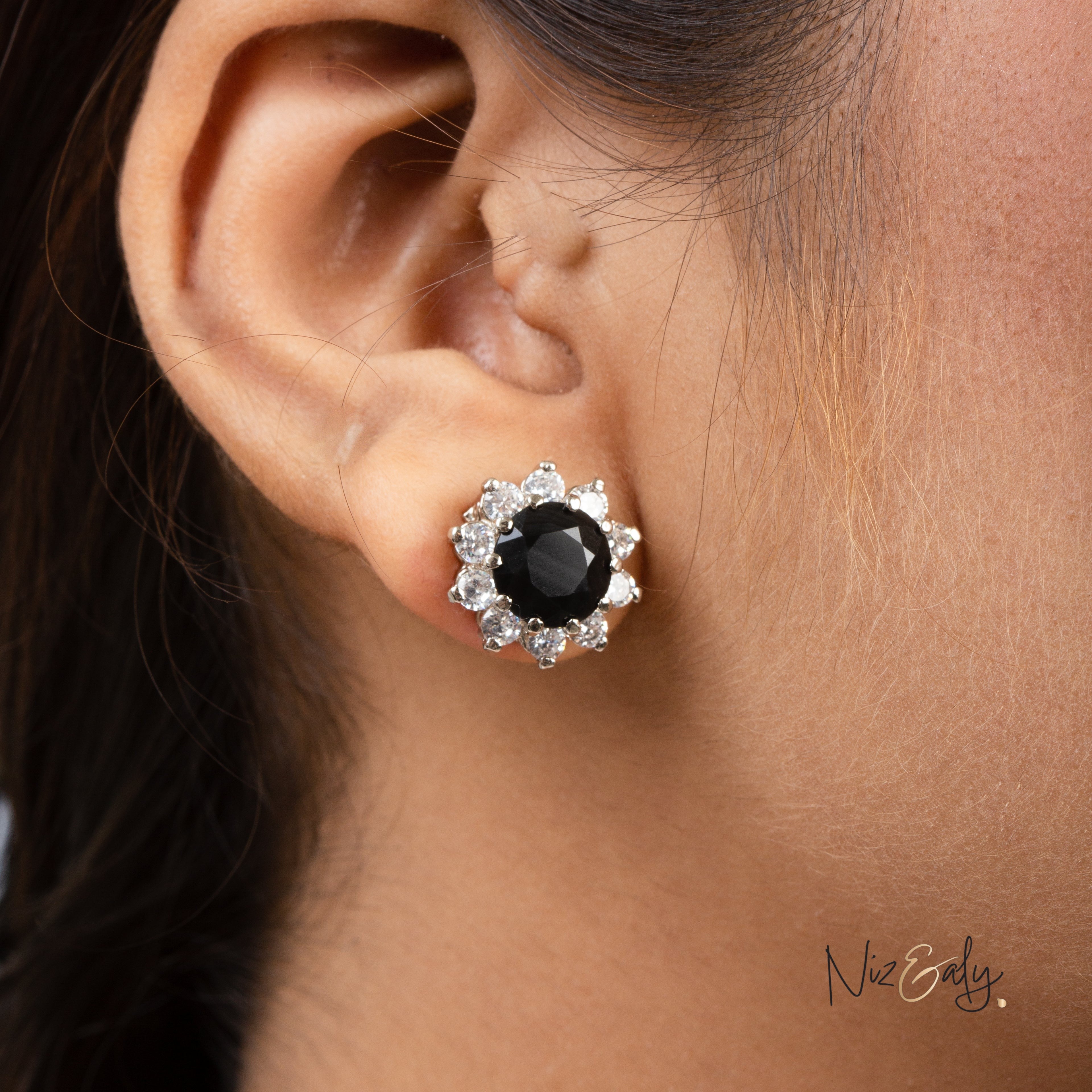 Niz & Aly black onyx stud earring surrounded by a halo of sparkling white crystals on a model's earlobe.