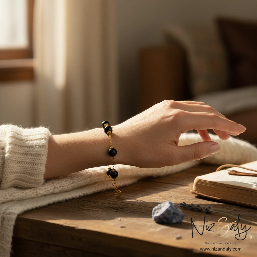 Niz & Aly gold-plated sterling silver bracelet with black onyx beads worn on a woman's wrist in a cozy setting