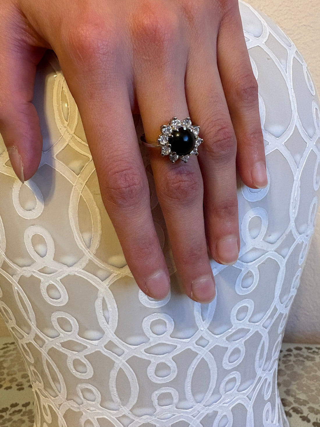 Niz & Aly natural black onyx ring with a halo of sparkling stones on a finger, featuring a classic elegant design.