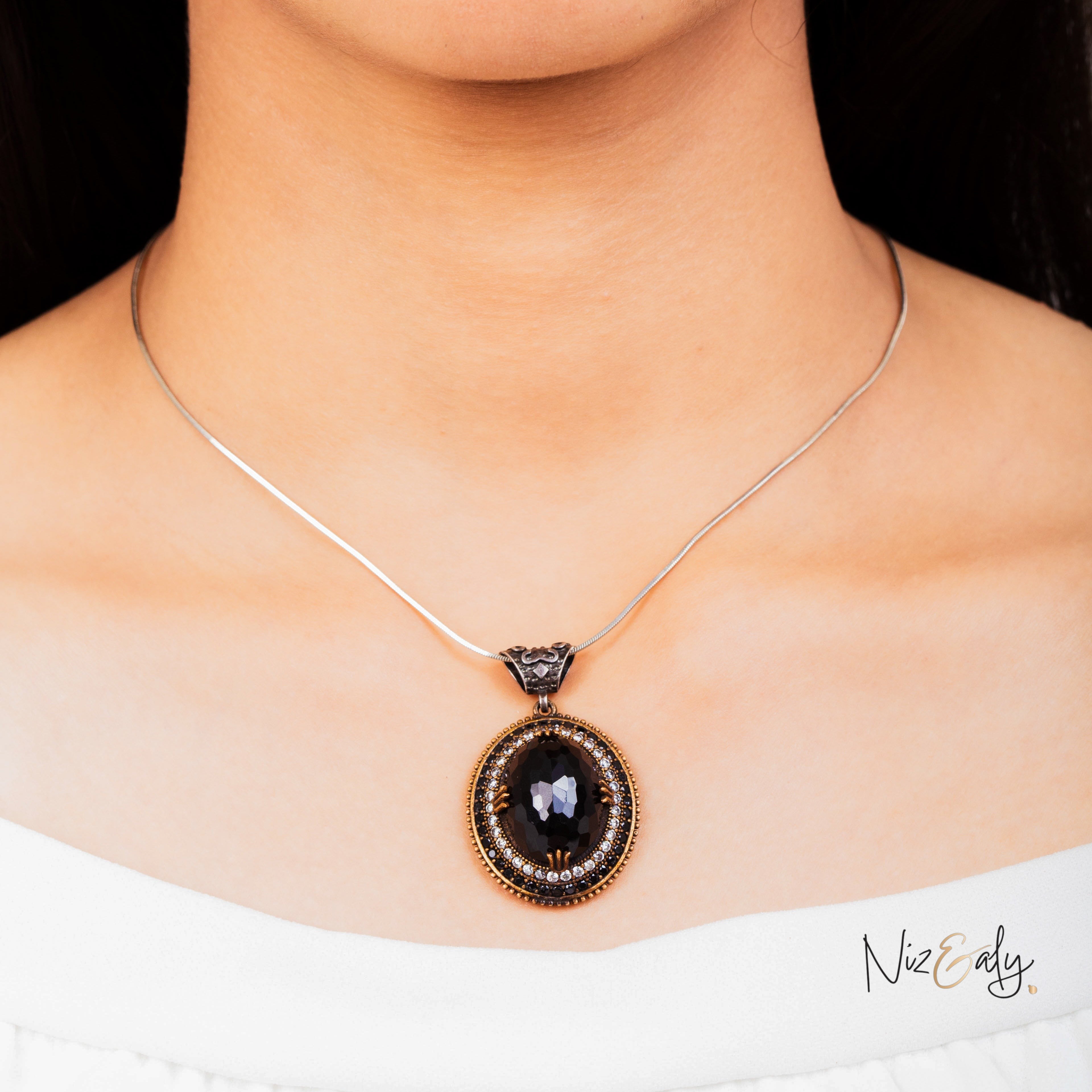 Niz & Aly faceted black onyx pendant necklace with VVS cubic zirconia stones on a silver chain worn around the neck