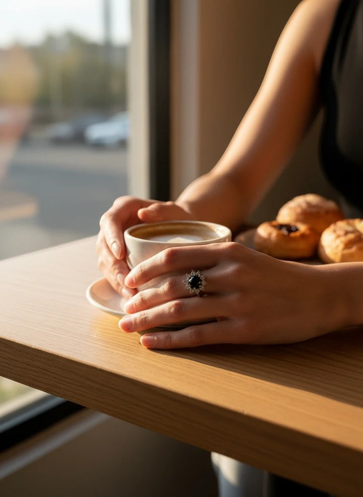Niz & Aly natural black onyx ring with a decorative setting worn on a hand holding a coffee cup at a cafe table.