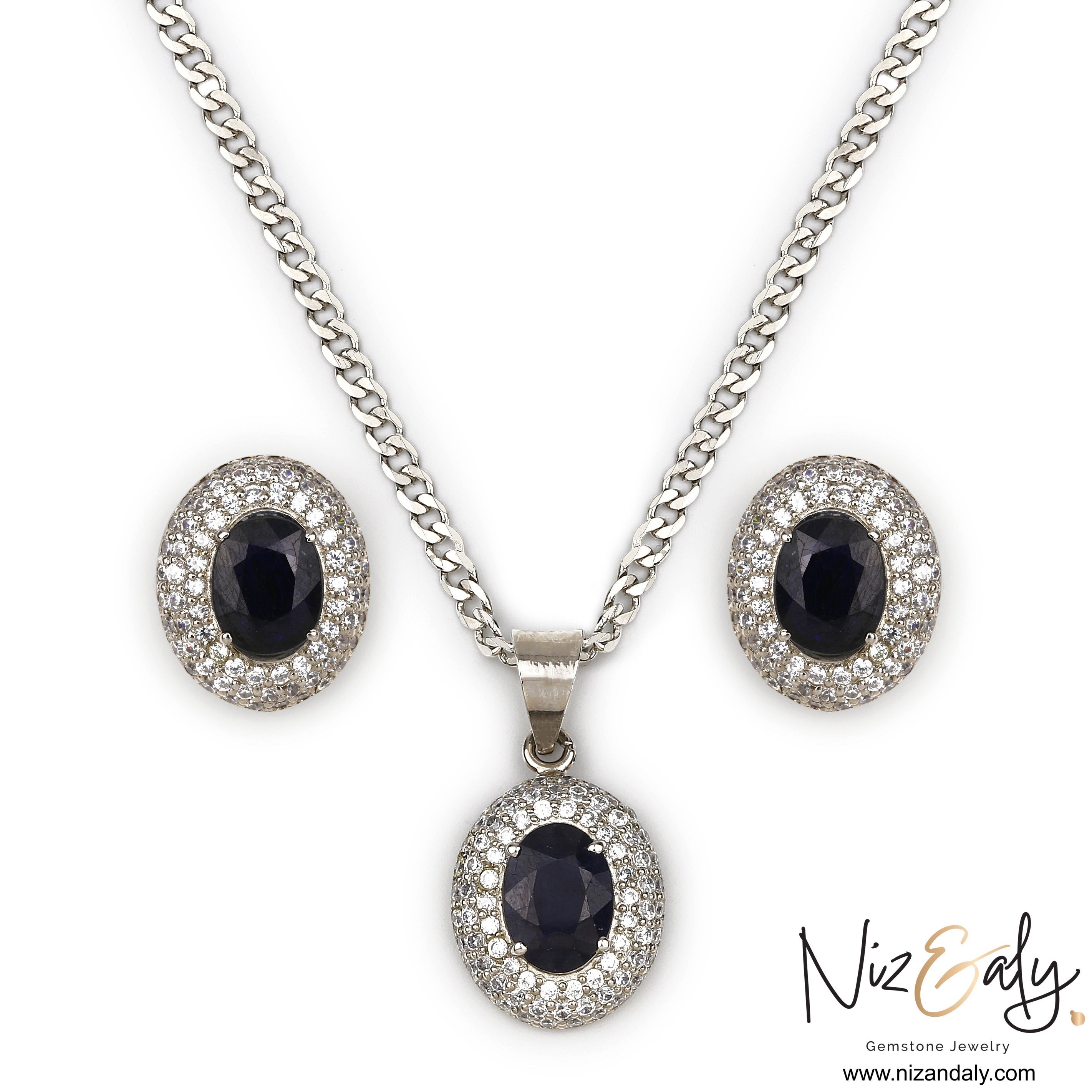 Niz & Aly royal blue sapphire pendant and stud earring set with diamond halo accents on a silver chain.
