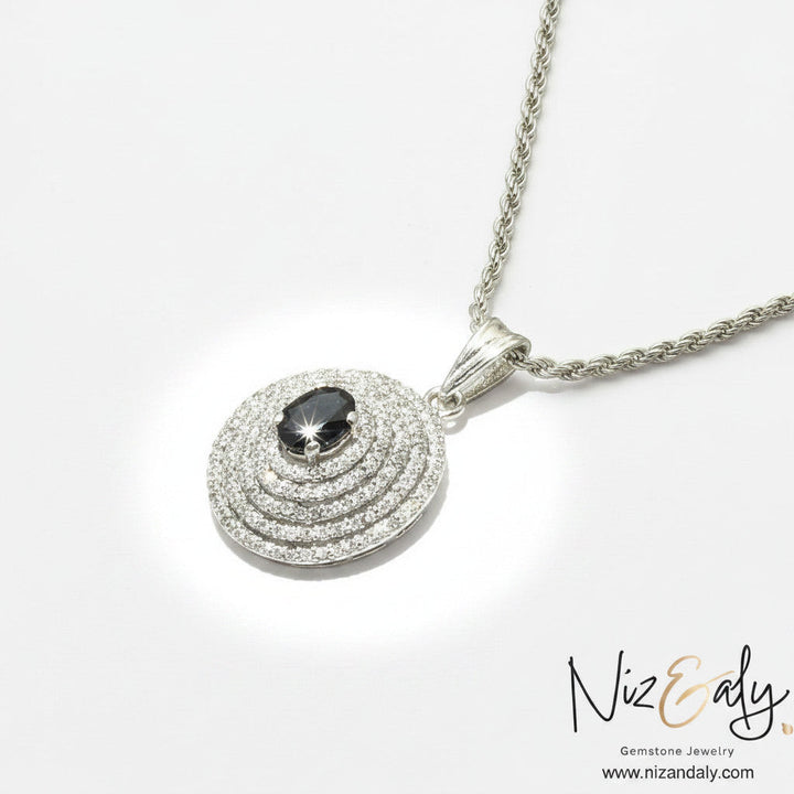 Niz & Aly Celestial Sapphire pendant necklace featuring a deep blue oval gemstone with concentric halos of diamonds.