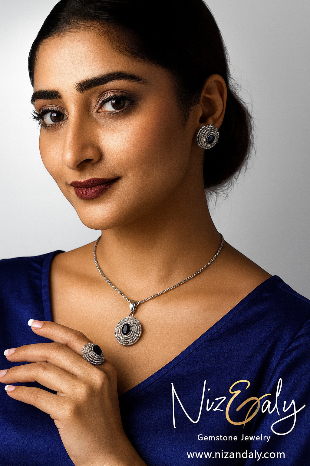 Niz & Aly Celestial Sapphire pendant necklace and earring set with deep blue gemstones and shimmering halo accents.