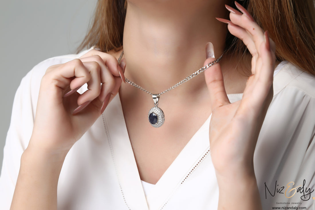 Niz & Aly royal blue sapphire pendant necklace worn by a woman in a white blouse