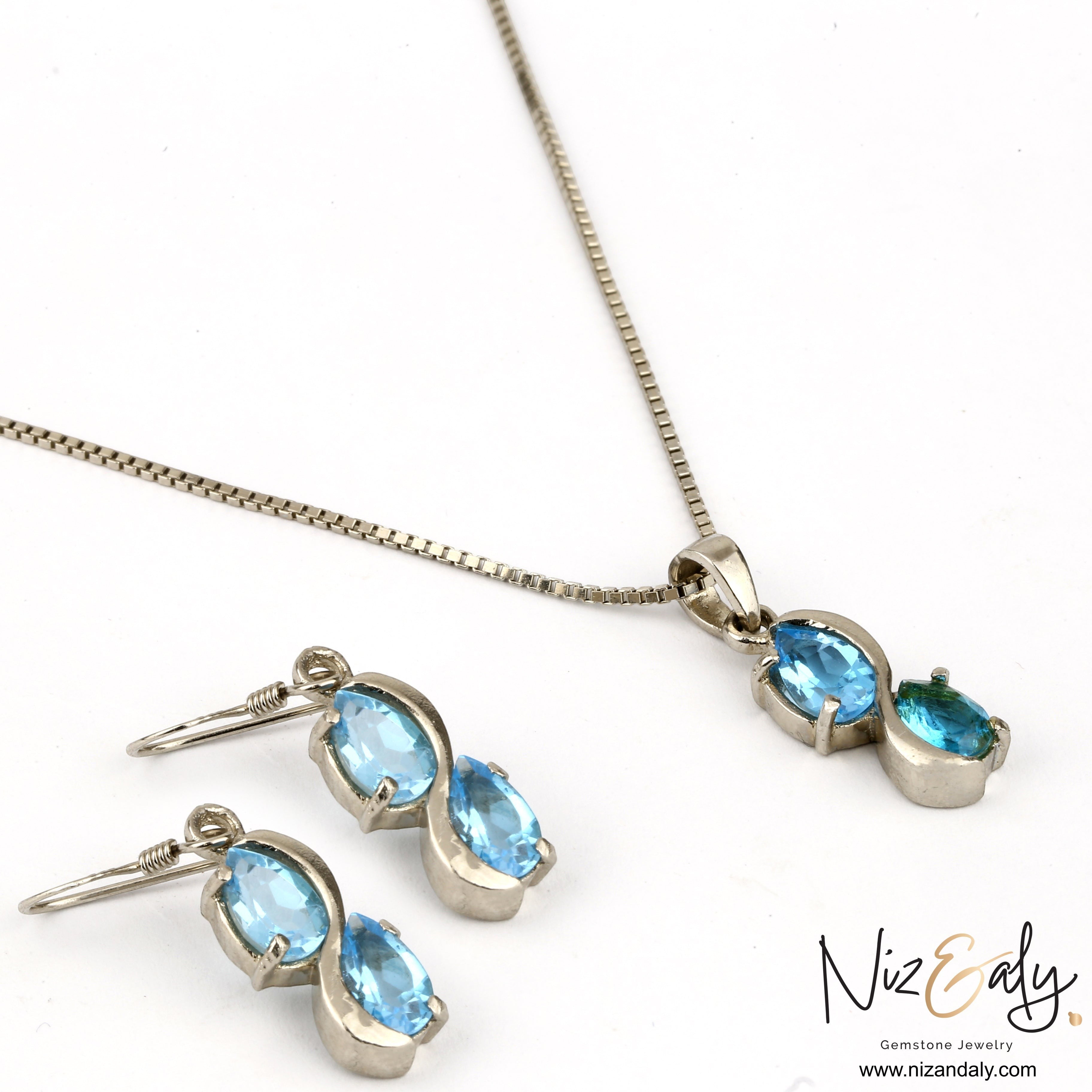 Niz & Aly sea blue double topaz drop pendant and earring set in silver, featuring shimmering pear-cut gemstones.