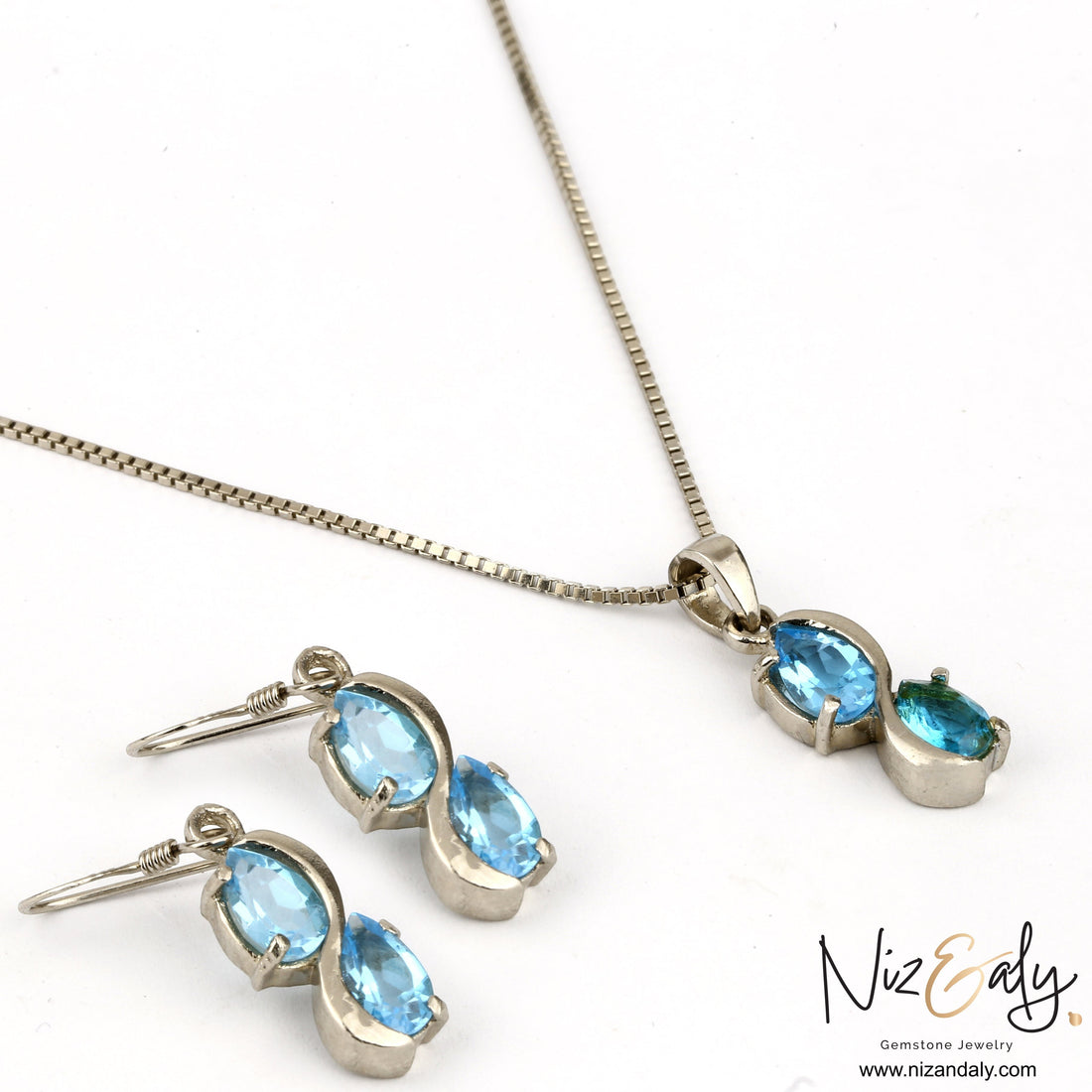 Niz & Aly sea blue double topaz drop pendant and earring set in silver, featuring shimmering pear-cut gemstones.