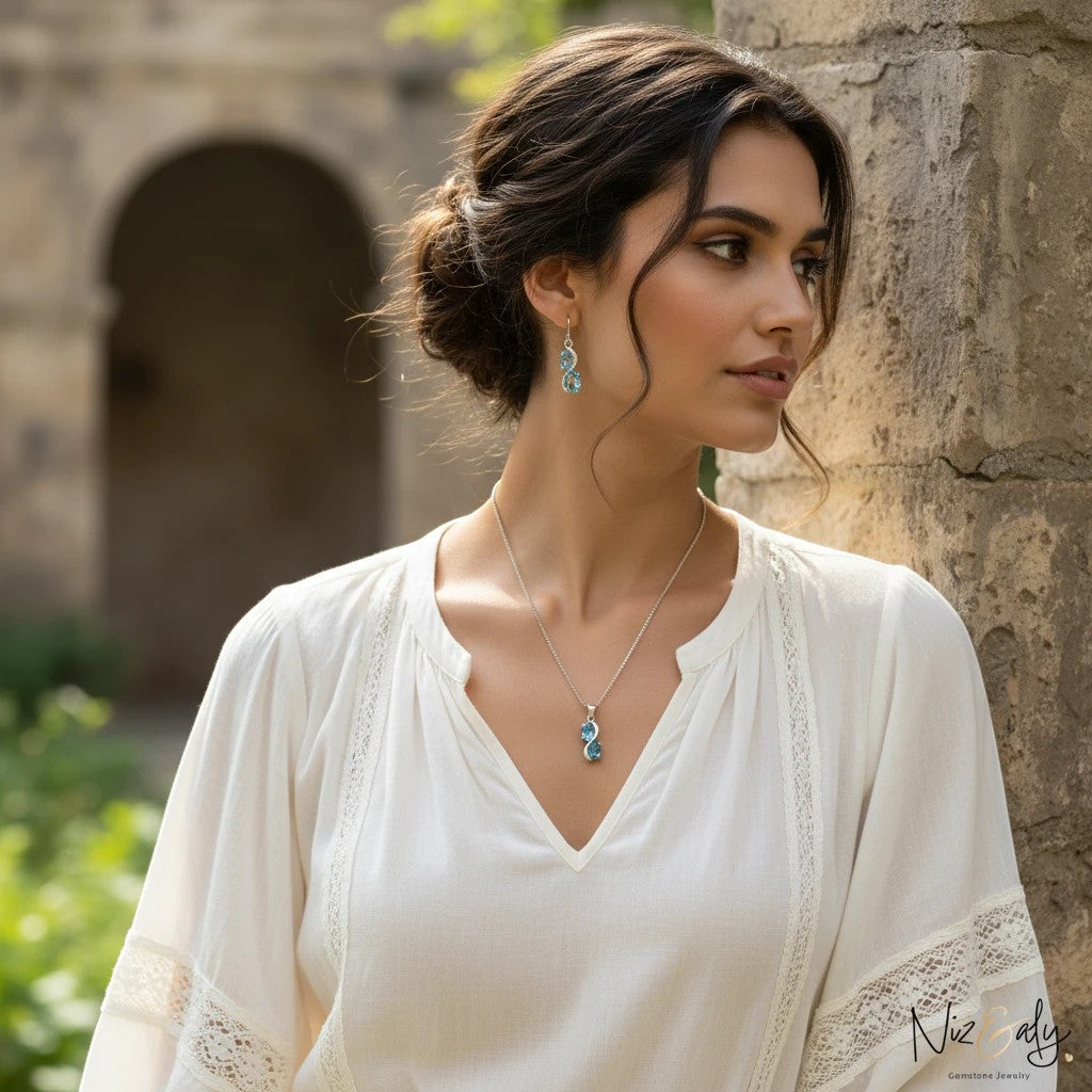 Niz & Aly sea blue double topaz pendant and earring set worn by a woman in a white lace blouse