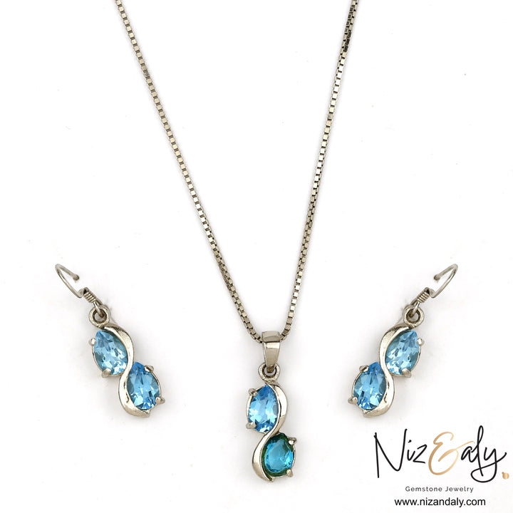 Niz & Aly sea blue double topaz drop pendant and earring set in silver, featuring shimmering oval gemstones.