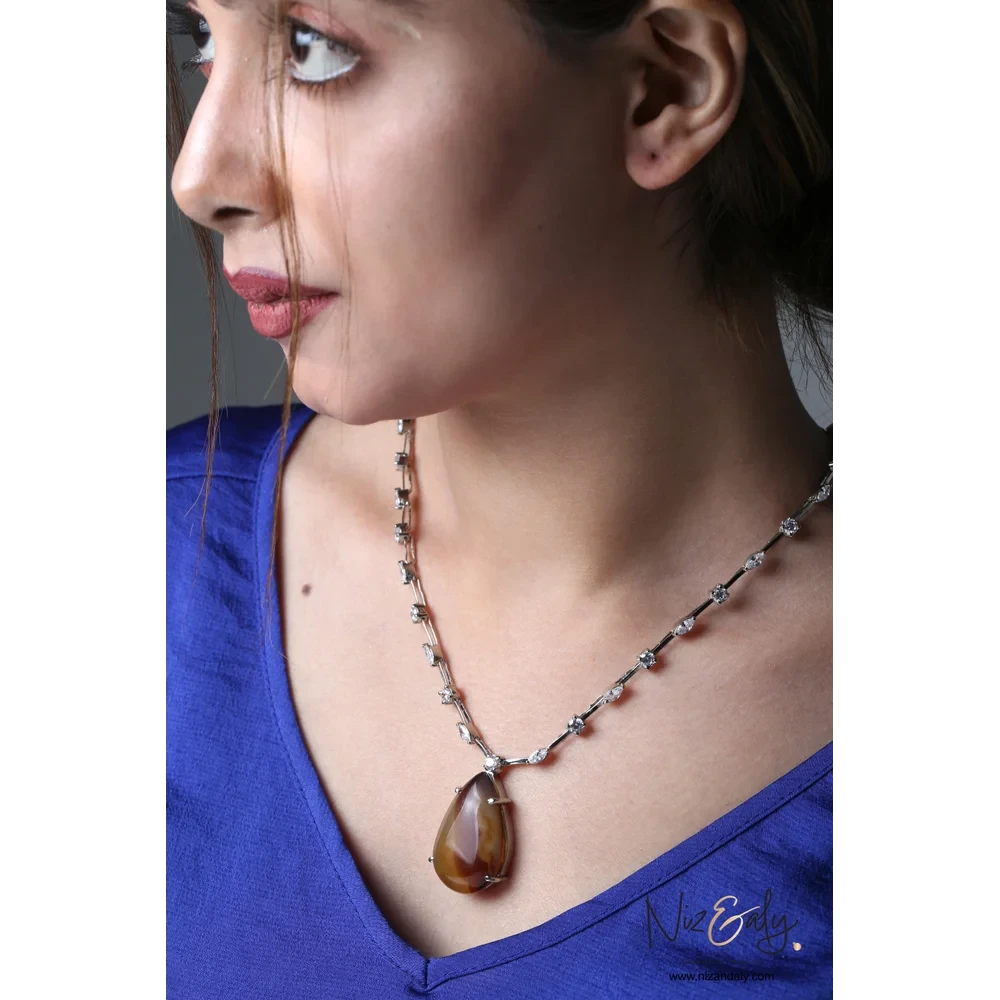 Niz & Aly brown agate statement necklace with cubic zirconia accents worn by a woman in a blue top.