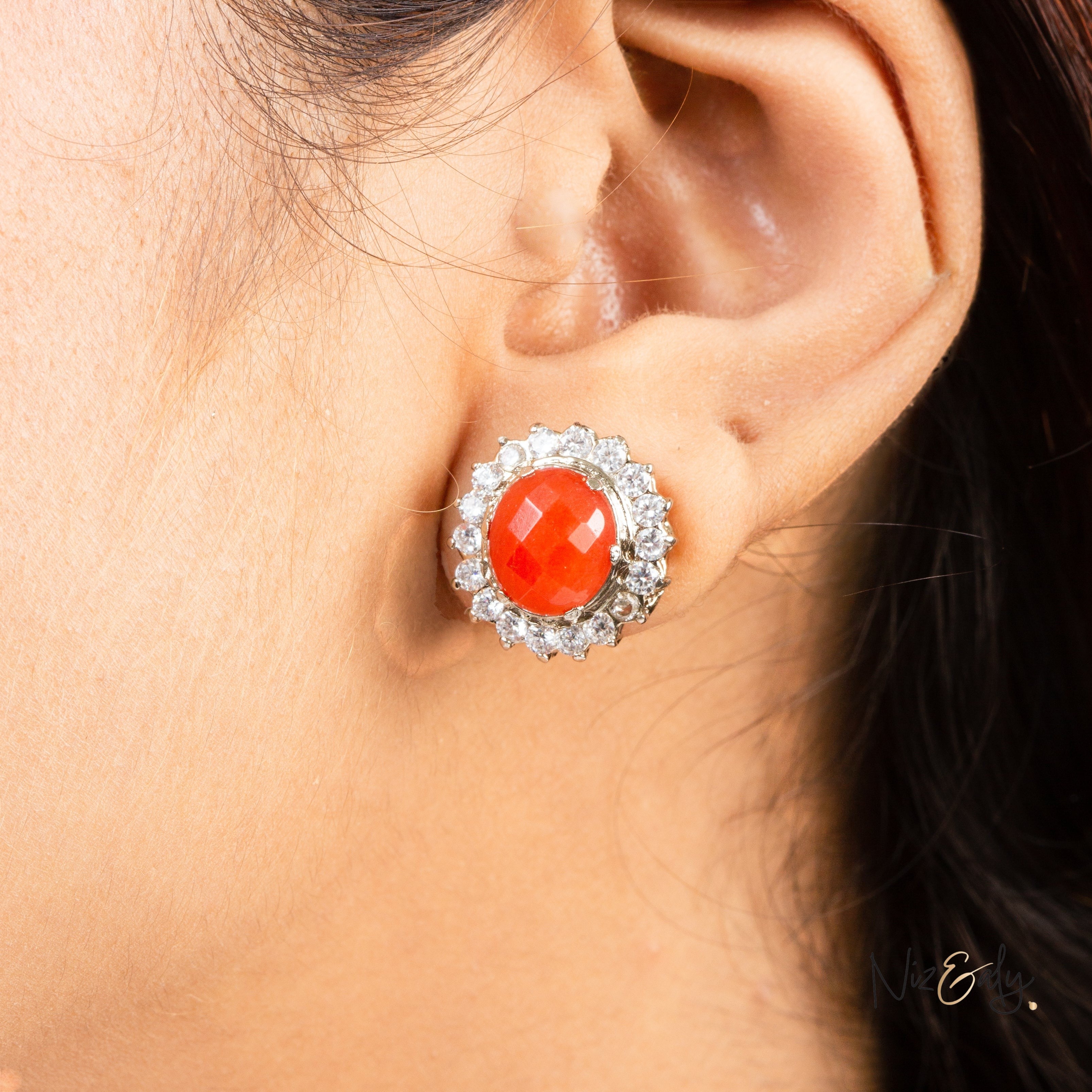 Niz & Aly carnelian stud earring featuring a vibrant orange-red oval stone surrounded by a halo of sparkling crystals.