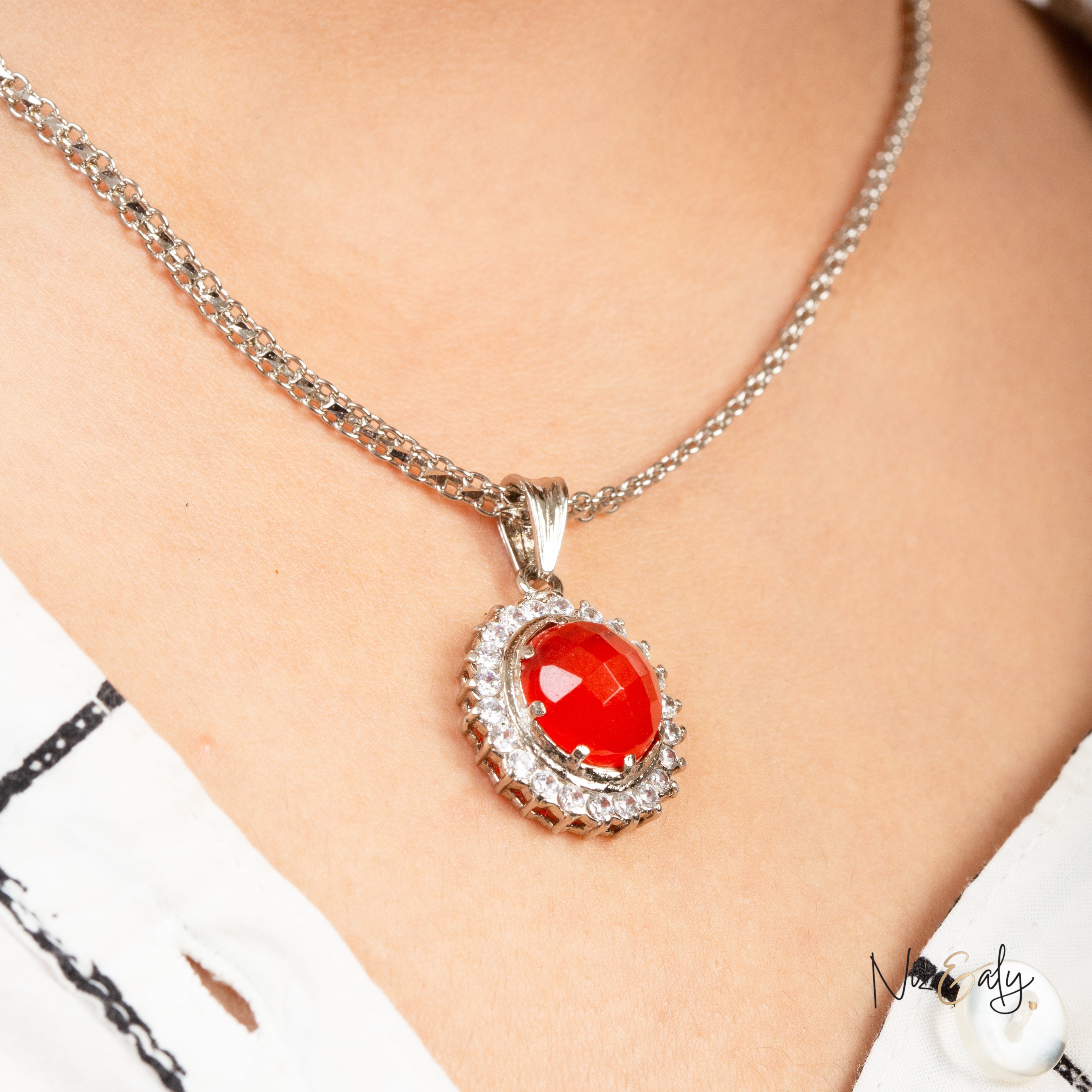 Niz & Aly Radiant Carnelian Locket featuring a polished orange-red stone surrounded by clear crystals on a silver chain