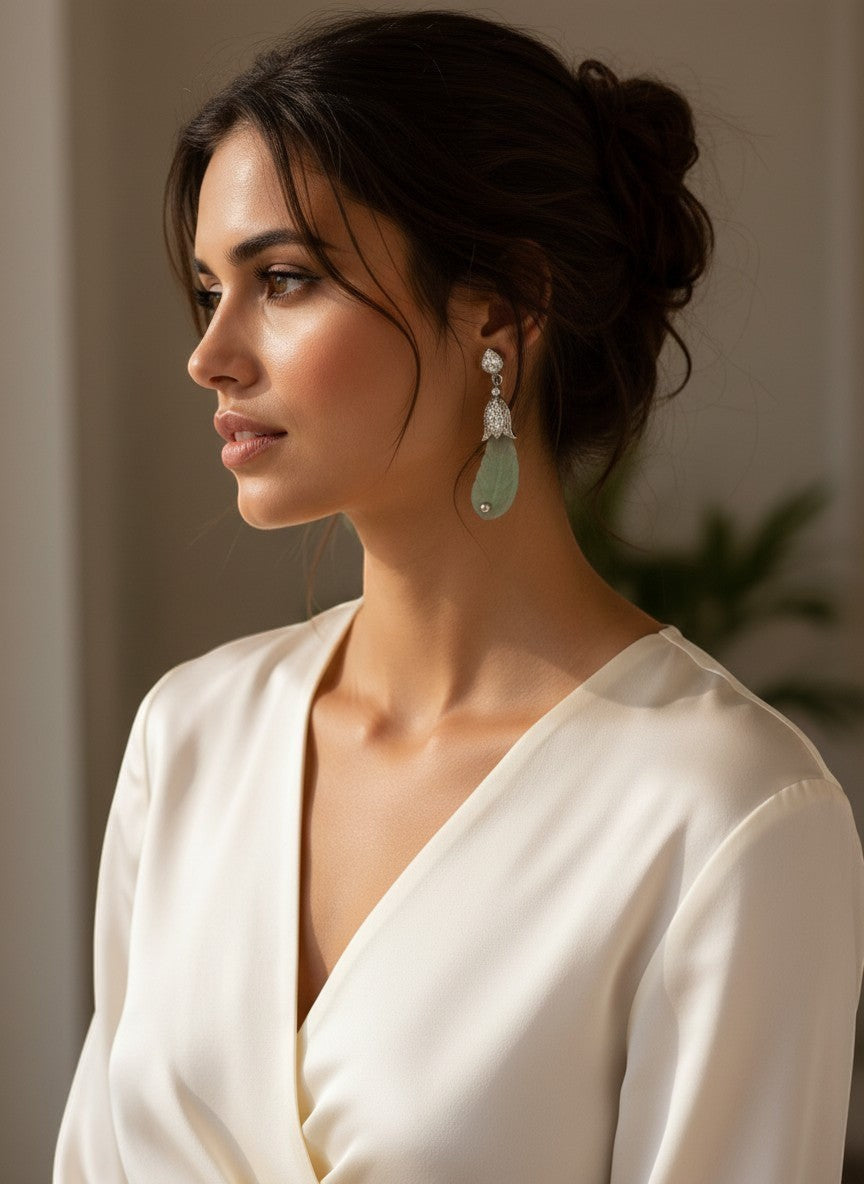 Niz & Aly carved prehnite drop earrings in soft green worn by a woman in a white silk blouse.