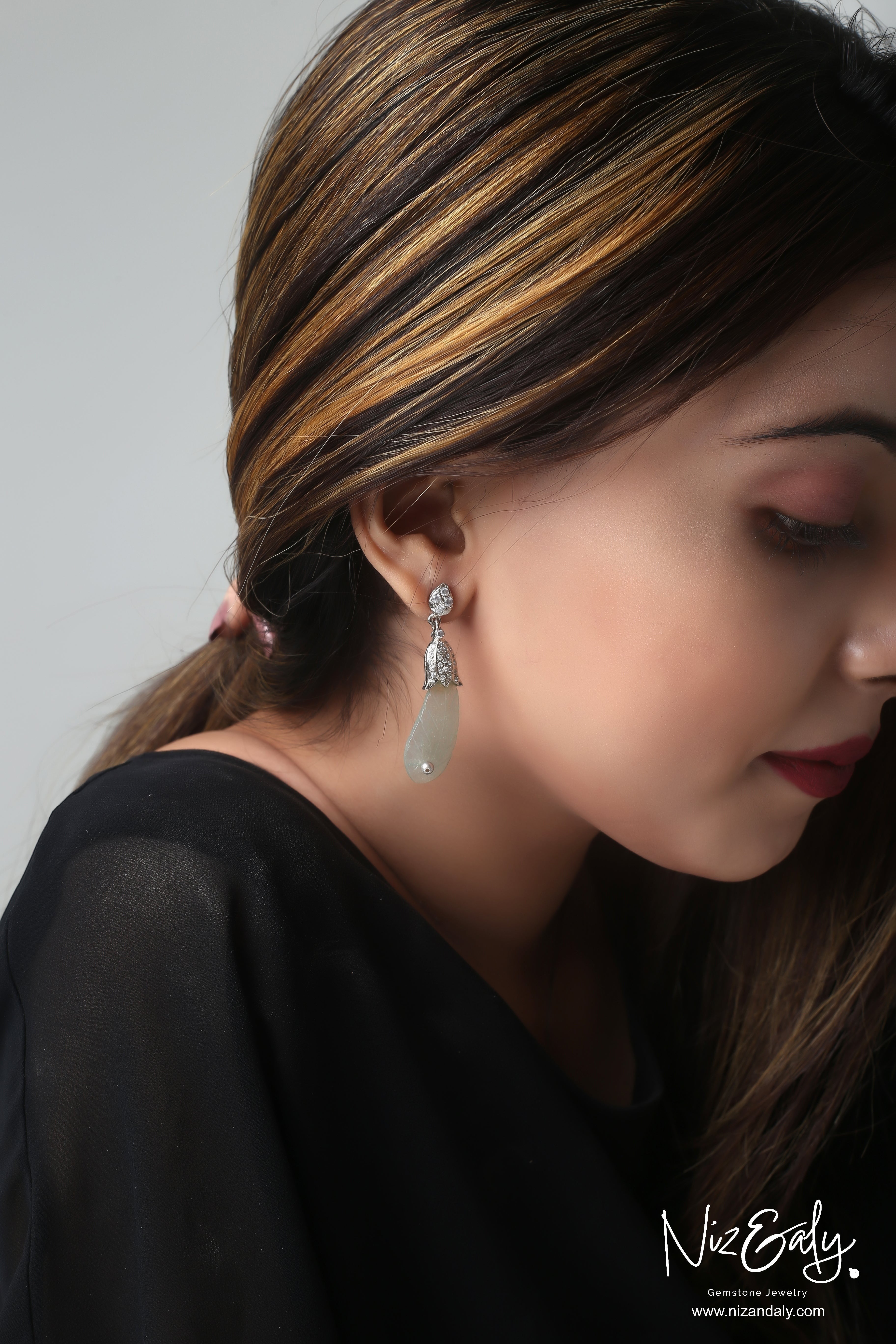 Niz & Aly carved prehnite drop earrings with silver detailing worn by a woman against a neutral background