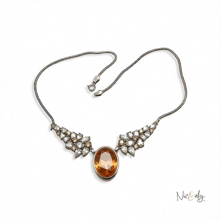 Niz & Aly Golden Hour statement necklace featuring a large oval champagne zirconia pendant with crystal accents.