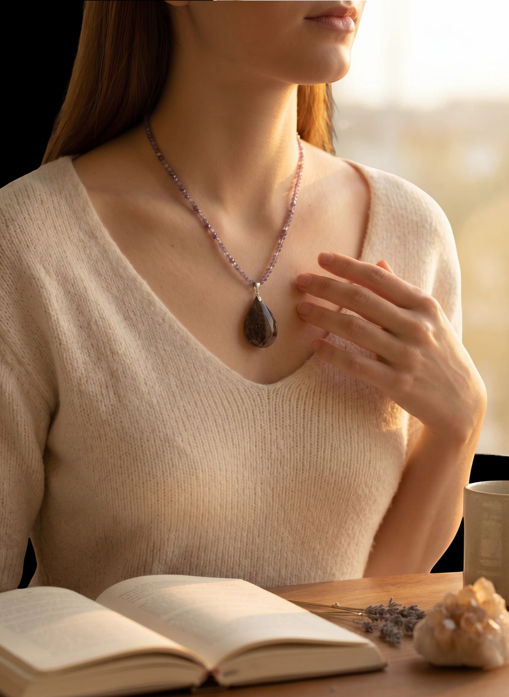 Niz & Aly teardrop Charoite pendant necklace with lavender beaded chain worn by a woman in a cream sweater