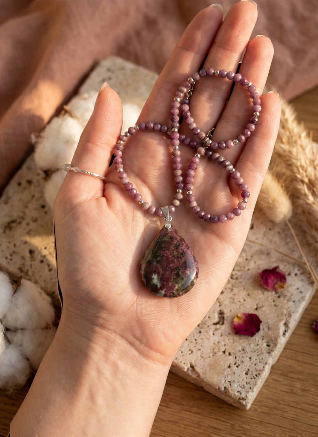 Niz & Aly teardrop Charoite pendant necklace with purple and lavender beaded chain held in a palm.