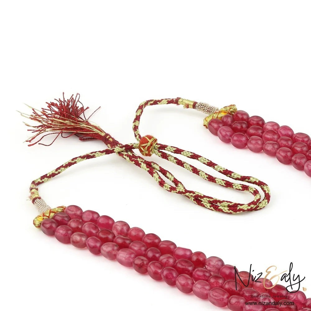 Niz & Aly triple strand cherry quartz beaded necklace with a decorative red and gold rope tie closure.