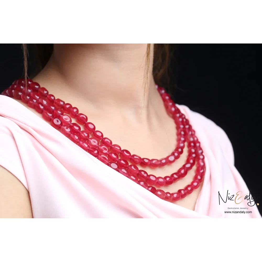 Niz & Aly triple strand necklace featuring polished translucent cherry quartz beads worn on a light pink top