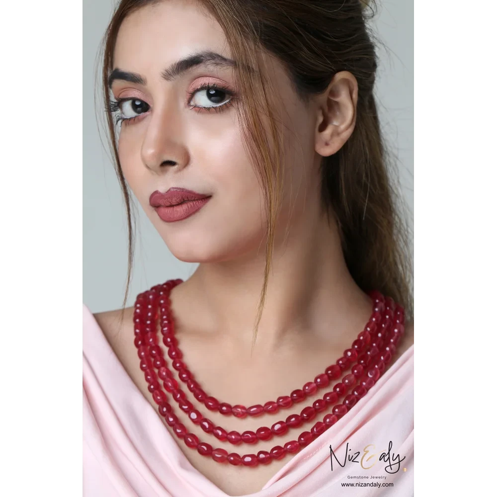 Niz & Aly triple strand cherry quartz beaded necklace worn by a woman in a pale pink top