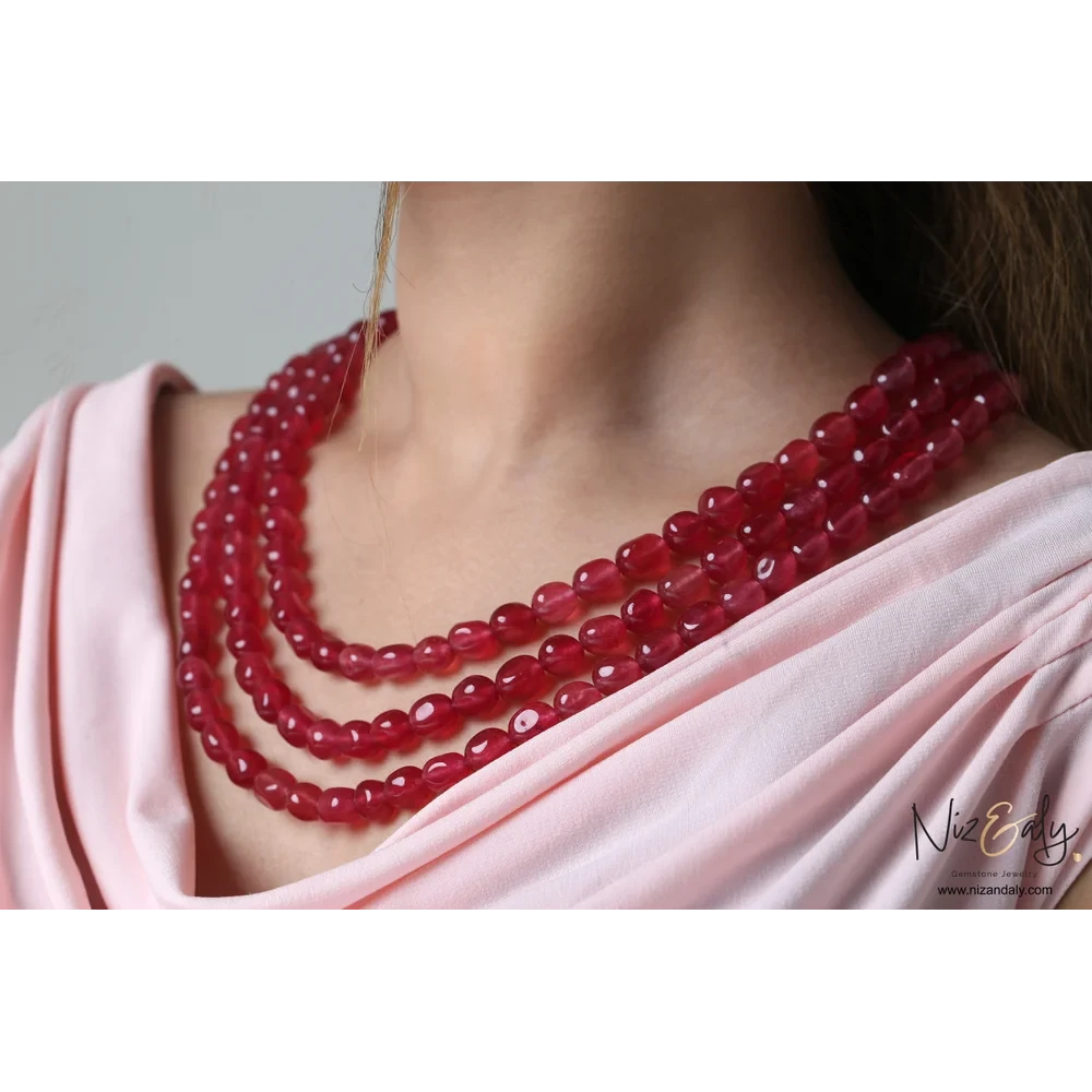 Niz & Aly triple strand necklace featuring polished translucent cherry quartz beads worn on a model in a pink top.